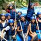 A cheerful group of rafters, children and adults alike, ready for river rafting, posing with paddles on a raft in Bali.