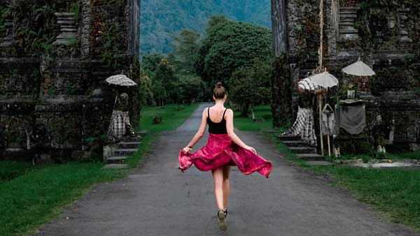 Woman twirling in a vibrant dress at the entrance of Handara Golf & Country Club in Bedugul, Bali.