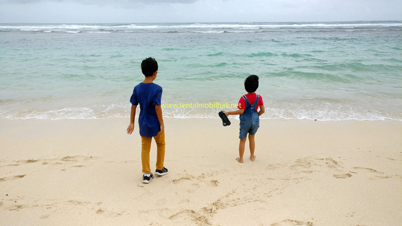 Two children joyfully playing on the white sands of Melasti Beach, Ungasan, Bali.