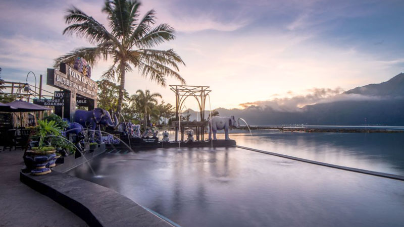 Toya Devasya Hot Spring Kintamani family relaxing in geothermal pool with Mount Batur background.