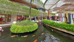 Elegant shopping boutiques along a serene koi pond in Kuta, Bali, with lush greenery and open-air ambiance.