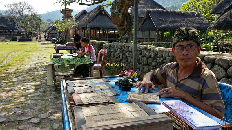 Local artisan demonstrating traditional lontar leaf writing in Tenganan Village.