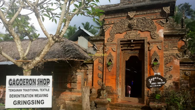 Traditional Balinese gateway at Tenganan Village with a sign for the Gringsing textile shop.