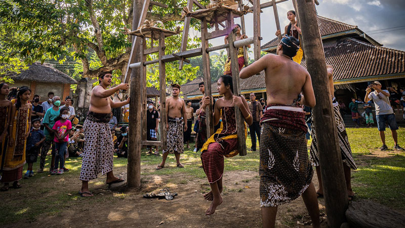 Villagers and visitors gather around traditional swings during a cultural event in Tenganan Village.