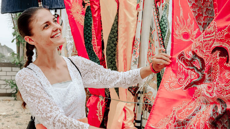 Joyful tourist admiring traditional Balinese textiles