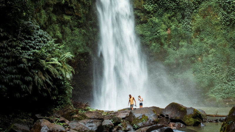 Two visitors are exploring the waterfall area.