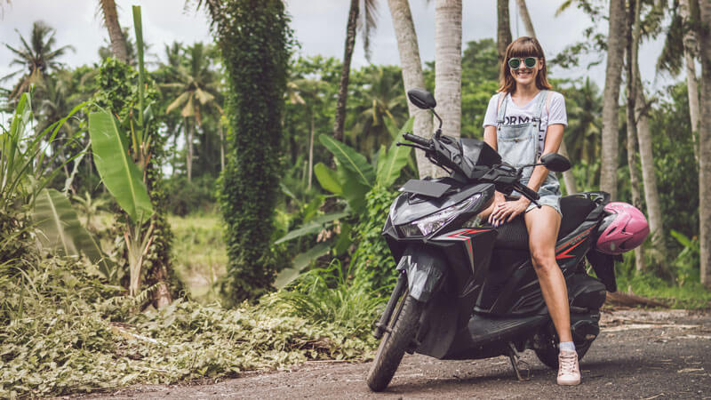 Tourist posing on a scooter amidst a lush Balinese landscape