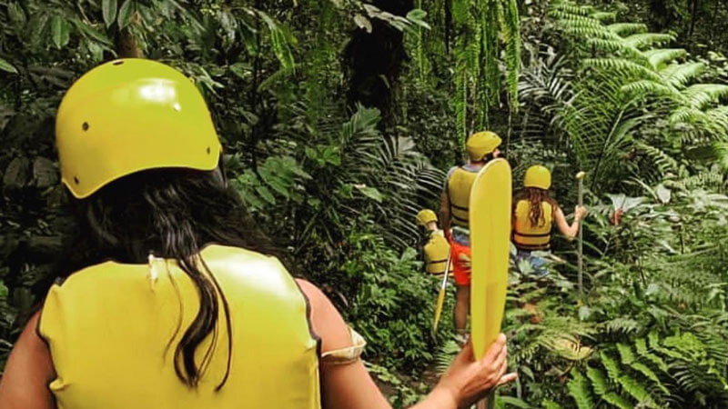 Tourists enjoying a guided nature trek and rafting adventure in Bali's lush scenery.