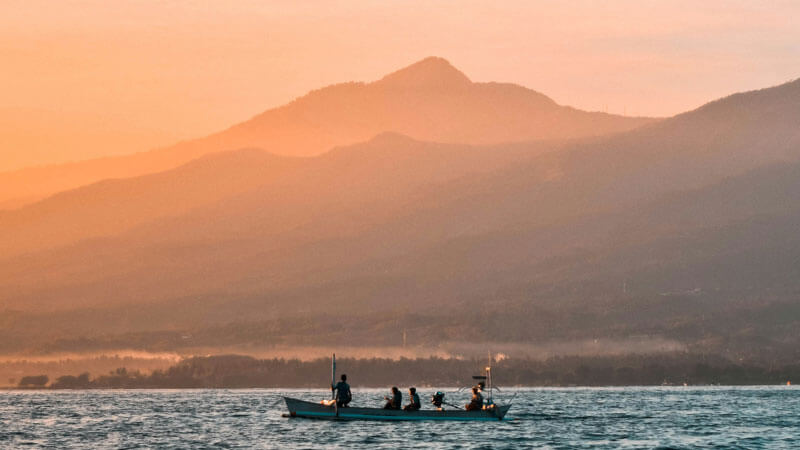 Traditional fishing boat on the waters of Lovina at sunrise with Bali mountains in the background. North Bali Visitor Guide