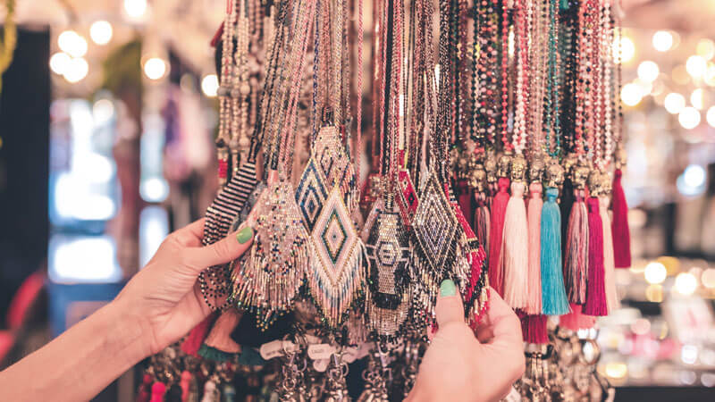 Hand selecting intricate beaded jewellery at a Bali market