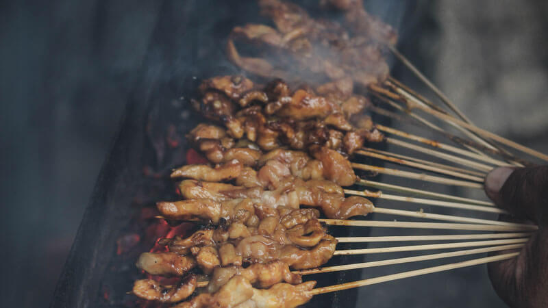 Sizzling traditional satay on skewers over a charcoal grill in North Bali