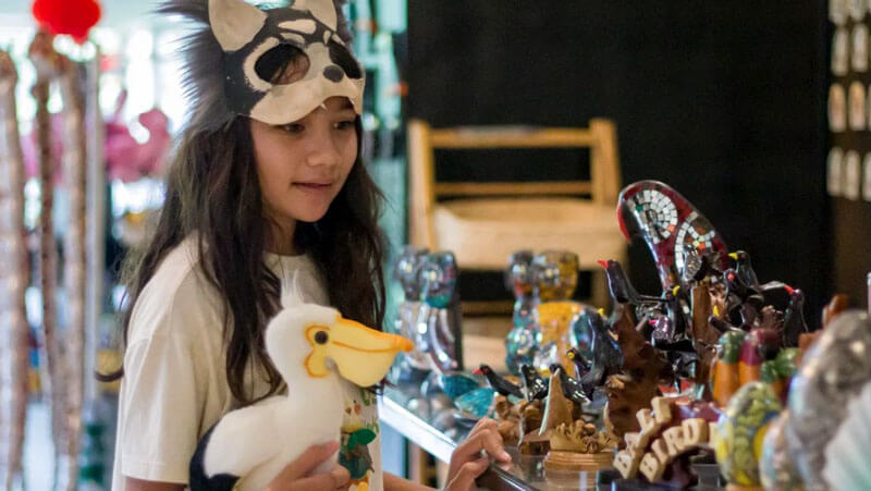 Young girl choosing souvenirs at Bali Bird Park souvenir shop