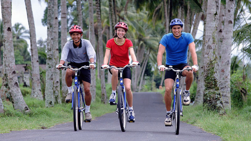 Happy cyclists on Bali Sobek Adventure surrounded by Bali's lush palm trees