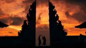 Silhouette of two people at the Gates of Heaven at Lempuyang Temple in Bali, with a vibrant sunrise sky in the background.