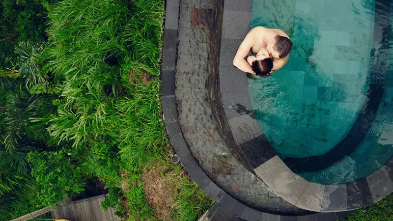 Romantic couple in a luxury infinity pool surrounded by tropical greenery in Bali.