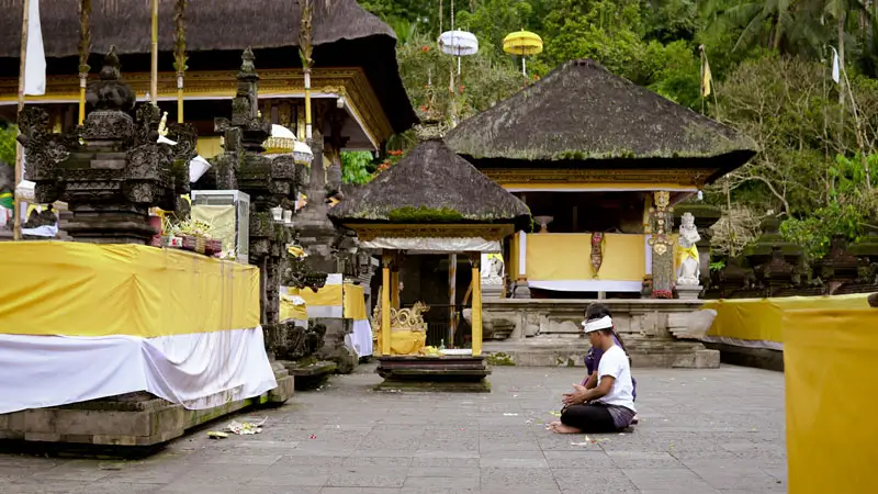 A Balinese Hindu devotee prays at a sacred inner temple courtyard, a revered water temple for spiritual cleansing and meditation.