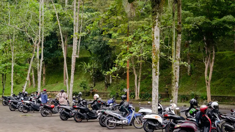 Motorcycle parking area at a Balinese sacred water temple, providing convenient access for visitors participating in purification rituals.