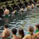 Visitors performing the Melukat purification ritual at Tirta Empul Temple Bali, a sacred Hindu water temple in Tampaksiring.