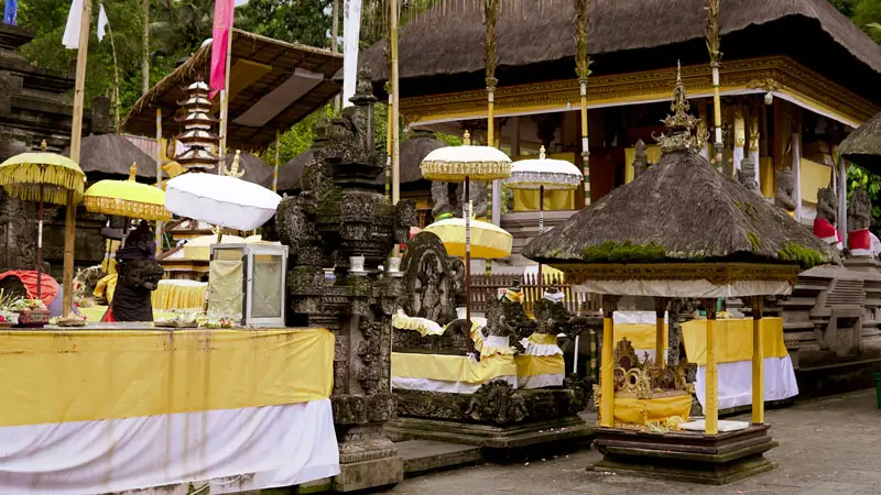 Sacred courtyard of Tirta Empul Temple in Bali, featuring Balinese shrines, traditional umbrellas, and intricate stone carvings used for Hindu ceremonies.
