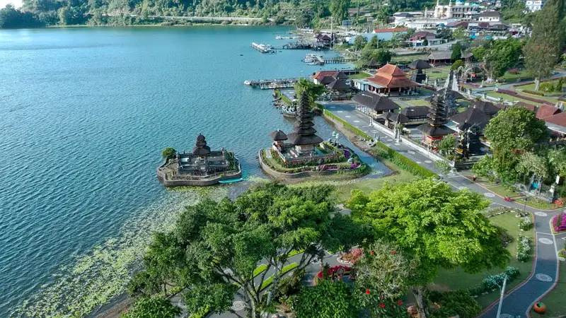 Aerial view of Bali highland temple complex with lake, pathways, and boat docks in Bedugul.