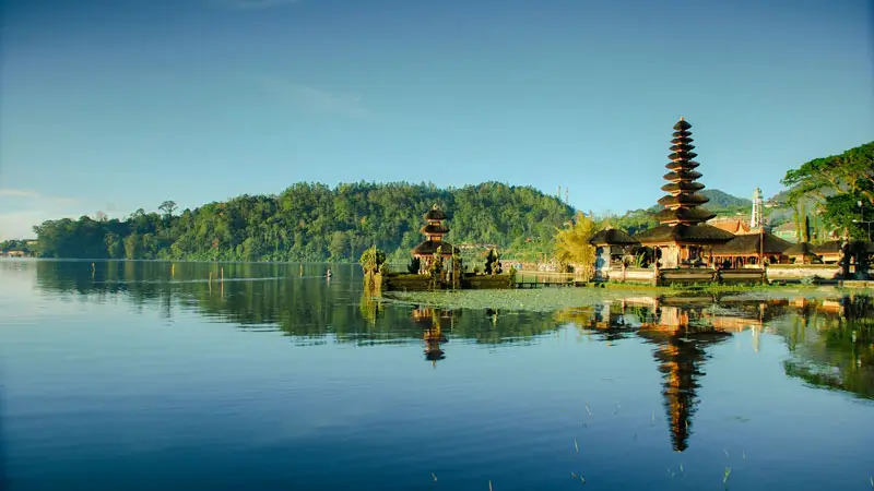 Serene morning reflections on Lake Beratan Bedugul Bali with distant shrines and calm water