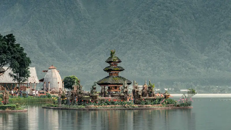 Ulun Danu Beratan Temple appears to float on Lake Beratan with mountain backdrop in Bedugul Bali