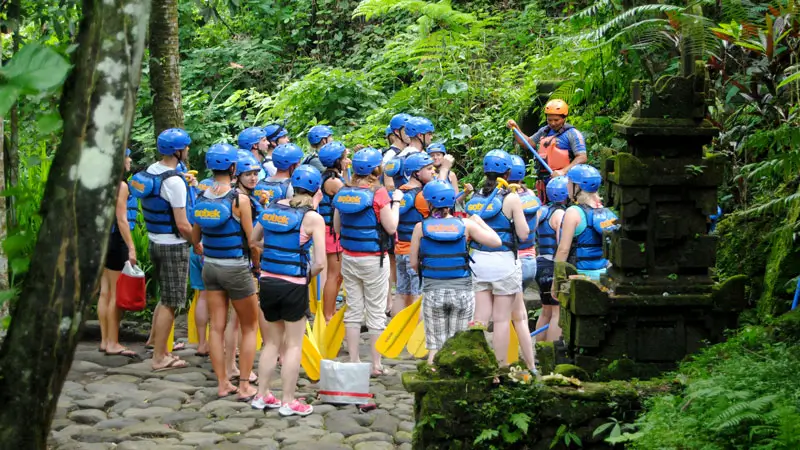 Group of travelers listening to rafting safety instructions from their guide.
