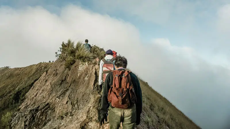 Hikers making their way up the rocky volcano slope at dawn
