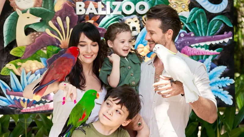 Family with young kids enjoying parrot encounter at Bali Zoo photo zone