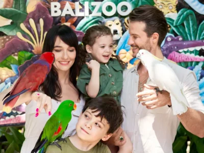 Family with kids posing with parrots at Bali Zoo photo zone