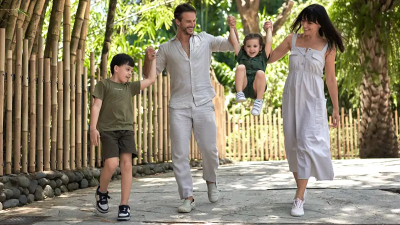Parents walking through Bali Zoo with happy kids on shaded path