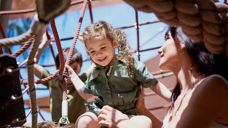 Toddler climbing safely in shaded play zone at Bali Zoo with parent supervision