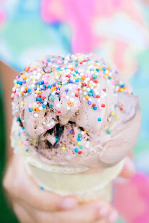 Child holding colorful ice cream cone with rainbow sprinkles