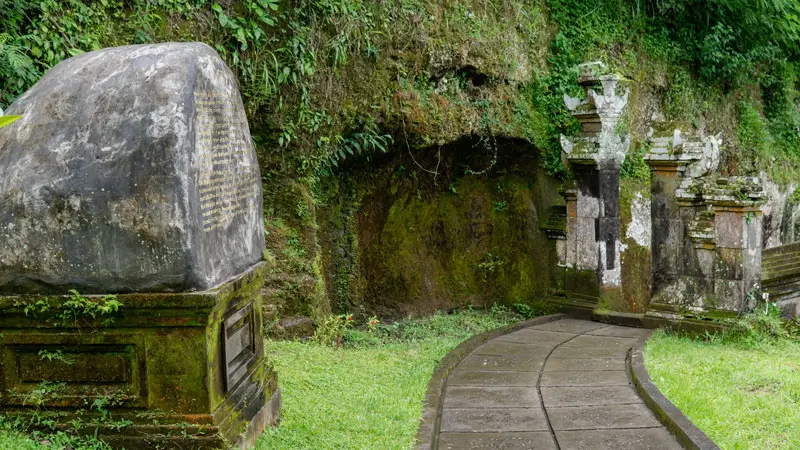 Sacred marker beside a mossy stone trail in Gianyar
