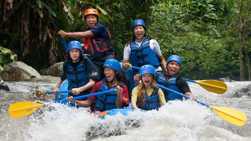 Family enjoying Sobek Rafting Ayung River with guide through scenic jungle rapids in Ubud Bali