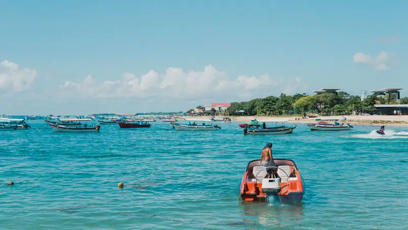 Morning window at a sheltered bay in Bali in December with small boats on calm water