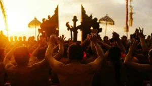 Uluwatu Kecak Fire Dance at sunset, chorus raising hands near the temple gate.