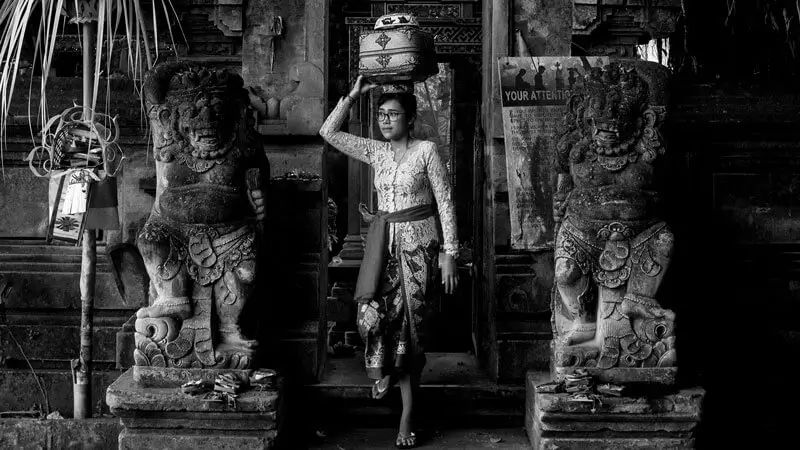 Balinese worshipper carrying offerings at temple entrance