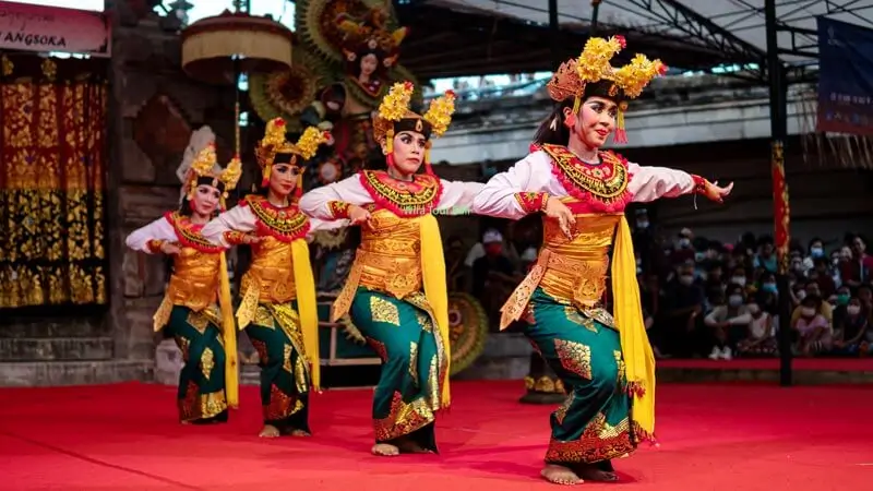 Balinese dancers performing a traditional legong-style routine on a red stage