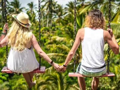 Couple holding hands on twin jungle swing in Ubud Bali during honeymoon