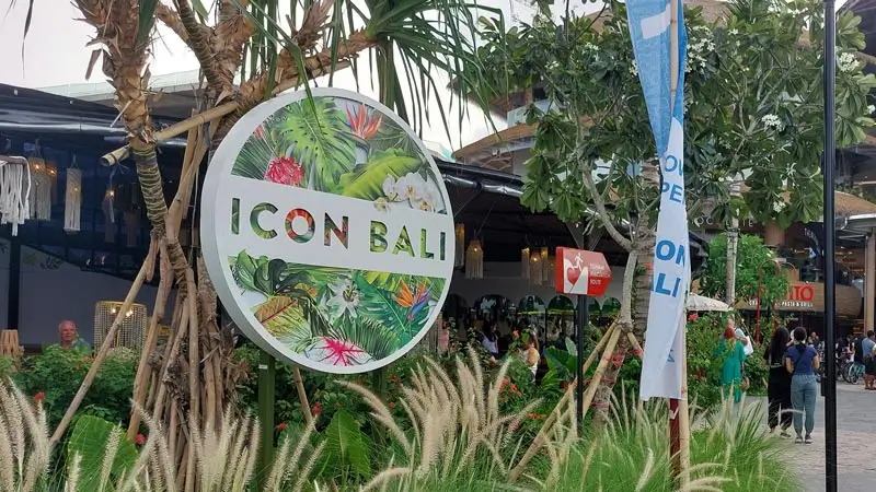 Entrance sign of Icon Bali mall in Sanur with plants and visitors