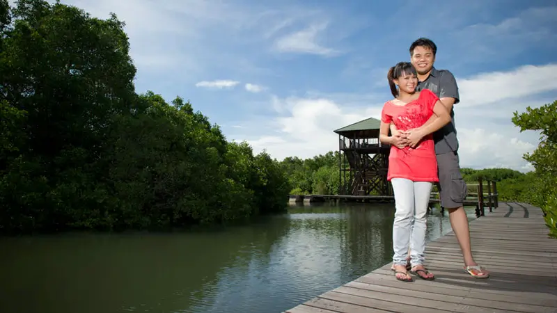 Couple standing on wooden boardwalk at Ngurah Rai Mangrove Forest Bali