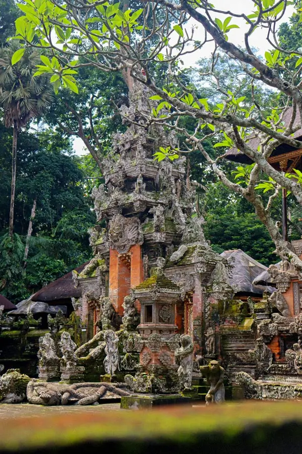 Central gate tower of Pura Dalem Agung Padangtegal framed by trees and statues in Ubud