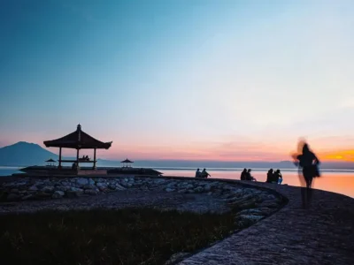Sunrise at Sanur Beach near Denpasar with families sitting by a seaside pavilion and calm water