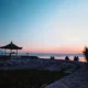 Sunrise at Sanur Beach near Denpasar with families sitting by a seaside pavilion and calm water
