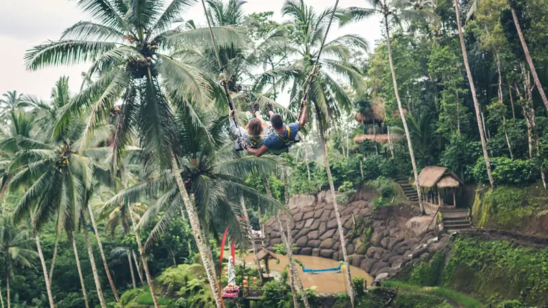 Couple on tandem Bali Swing in Ubud flying above tropical valley