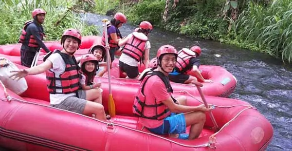 Smiling group relaxing in a red raft on calm river water.