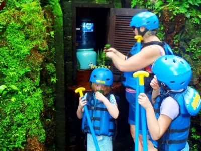 Parent with two children wearing helmets and life jackets before kids rafting