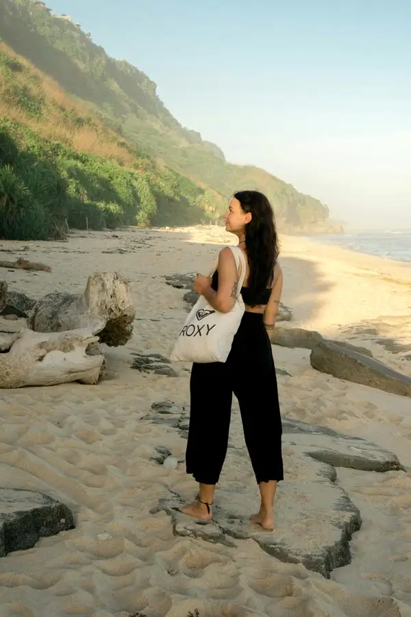 Woman in a light black outfit walking on a Bali beach