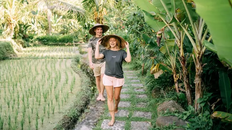 Travelers in casual clothes walking through a Bali rice field